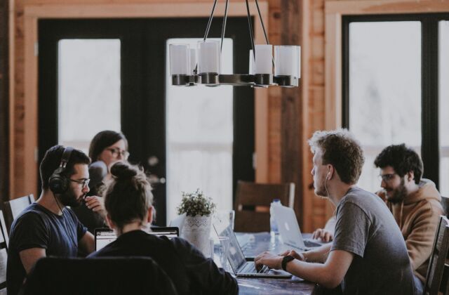 Mehrere Menschen sitzen zusammen an einem Tisch und arbeiten