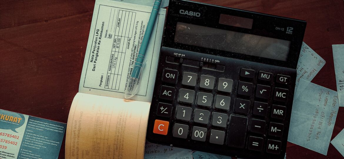 Taschenrechner und Checkbücher liegen auf einem Tisch verteilt
