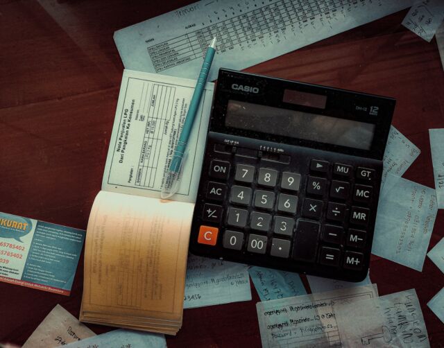 Taschenrechner und Checkbücher liegen auf einem Tisch verteilt