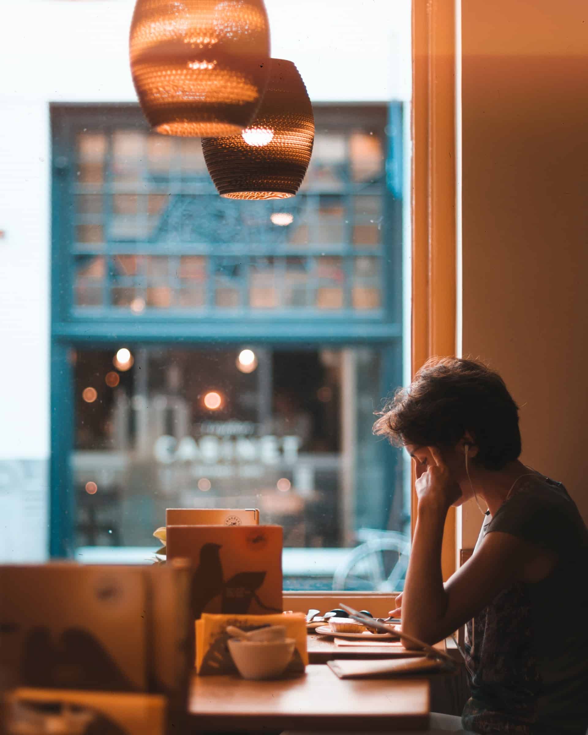 Eine Person sitzt vor einem Fenster und arbeitet konzentriert am Laptop