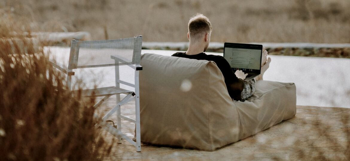 Ein Mann am Strand, der an seinem Laptop arbeitet