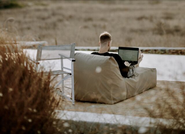 Ein Mann am Strand, der an seinem Laptop arbeitet