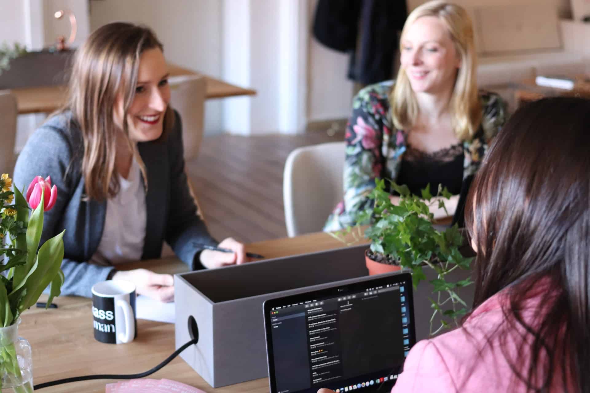 Drei Frauen sitzen gemeinsam an einem Tisch und unterhalten sich