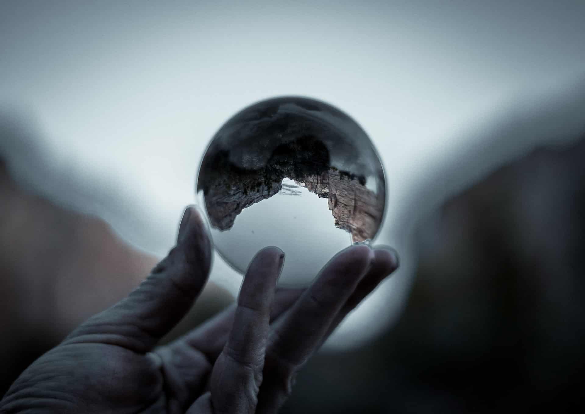 Eine Person hält eine Glaskugel in der Hand, in der sich die Umgebung kopfüber spiegelt