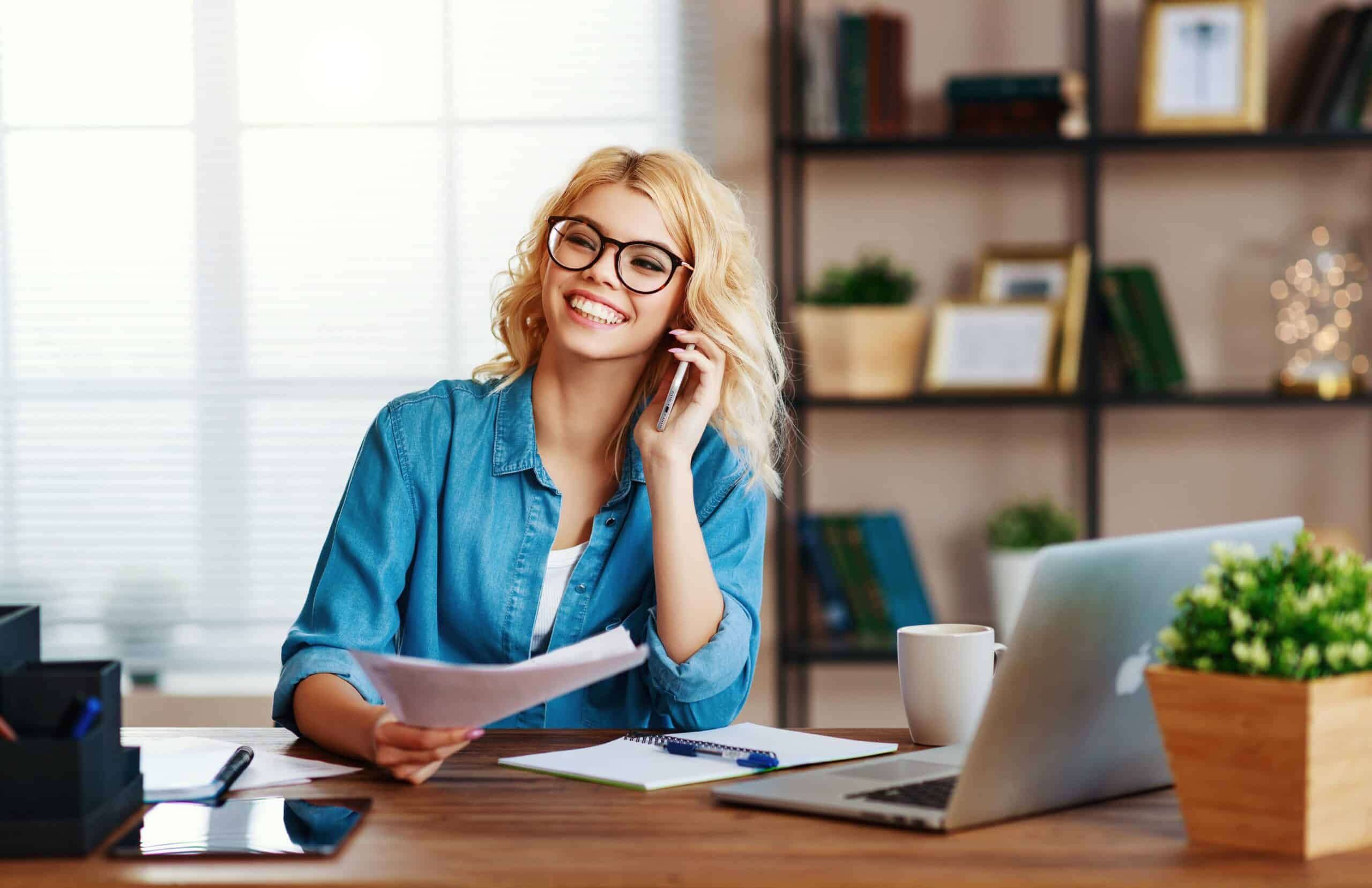 Eine junge Frau arbeitet im Homeoffice und ist fröhlich