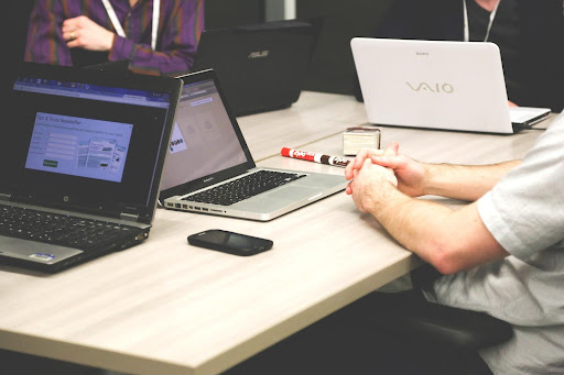 Mehrere Personen sitzen mit ihren Laptops an einem Tisch