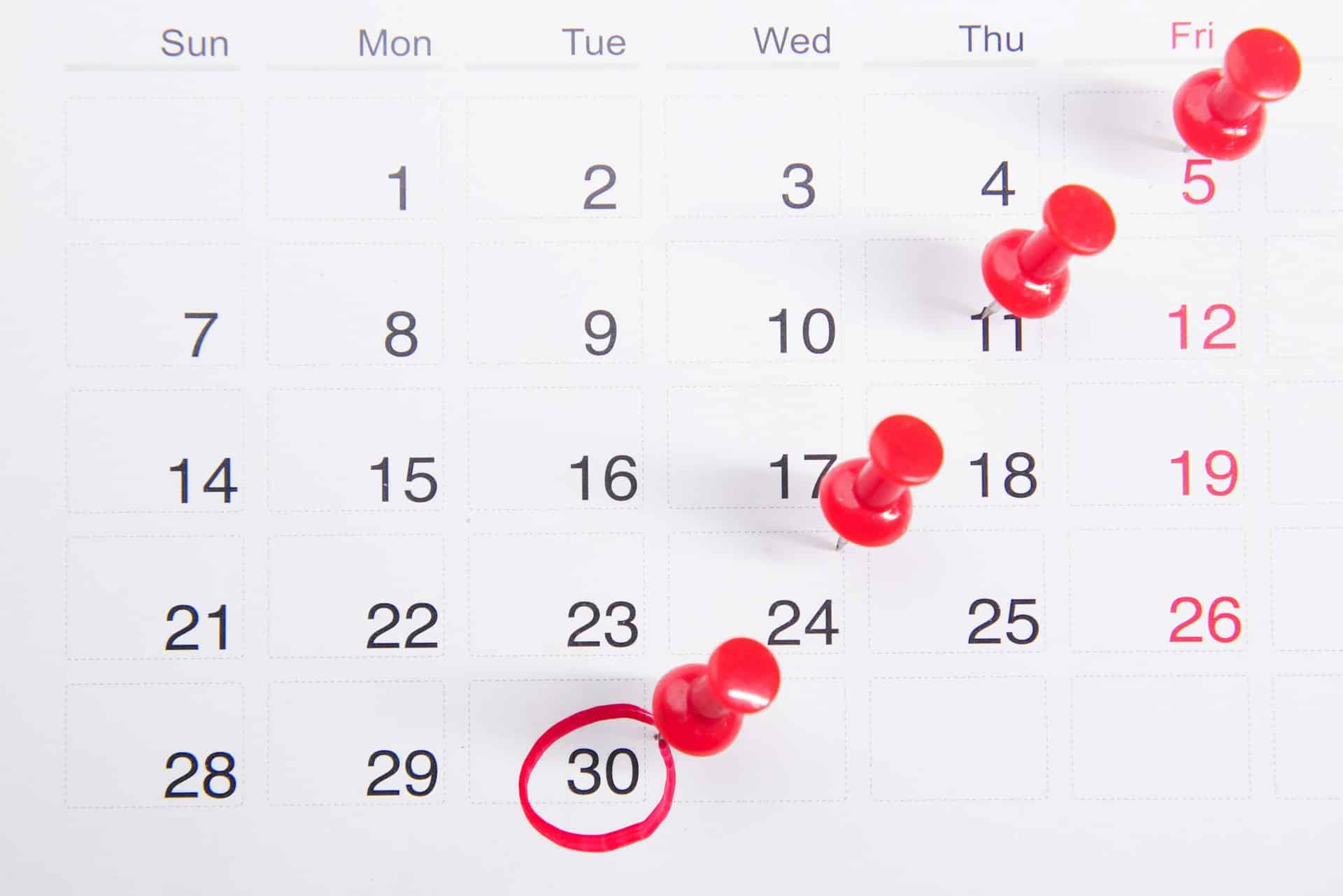 Ein Kalender mit roten Stecknadeln und einem eingekreisten Datum
