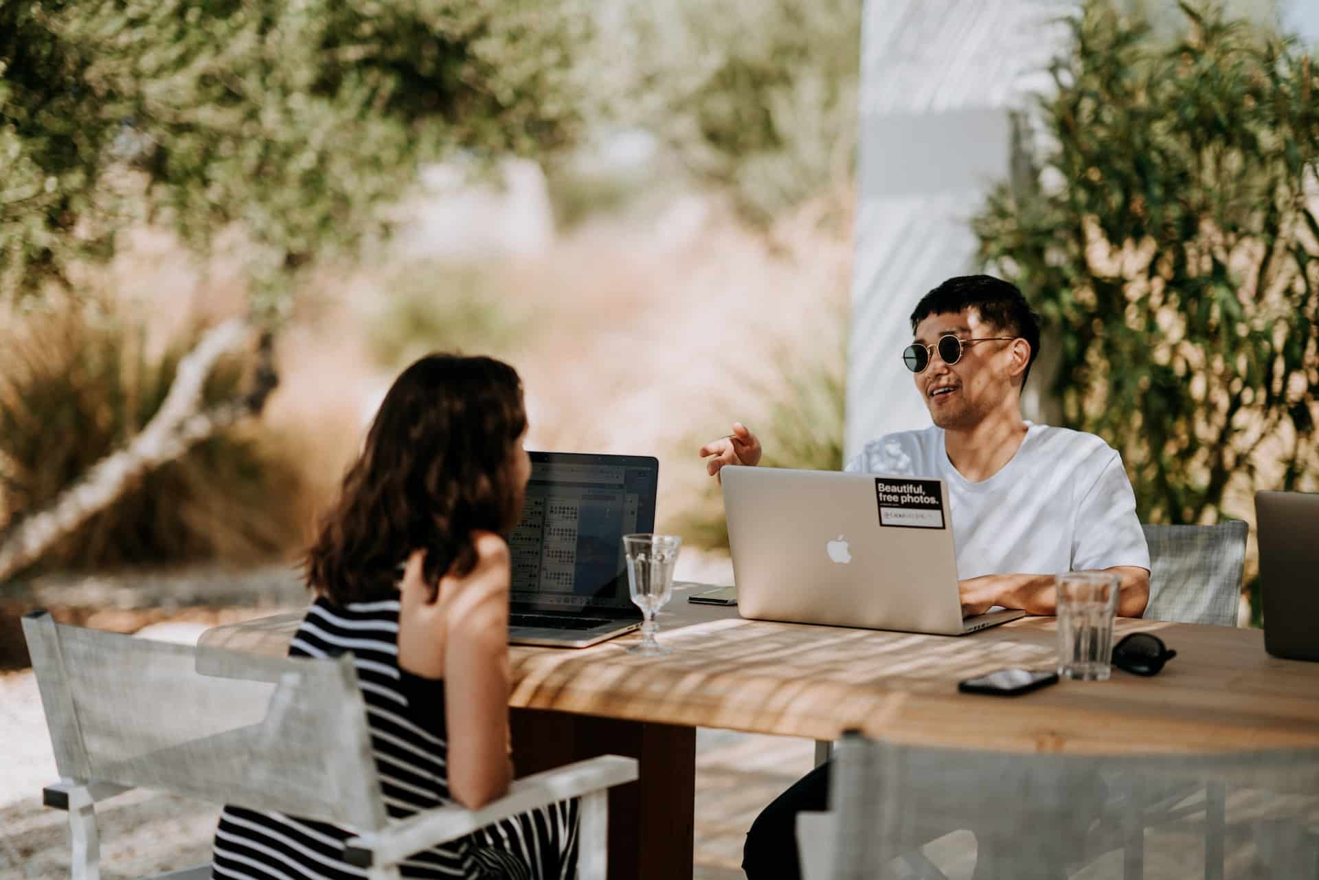 Zwei Personen sitzen im freien und arbeiten an ihren Laptops