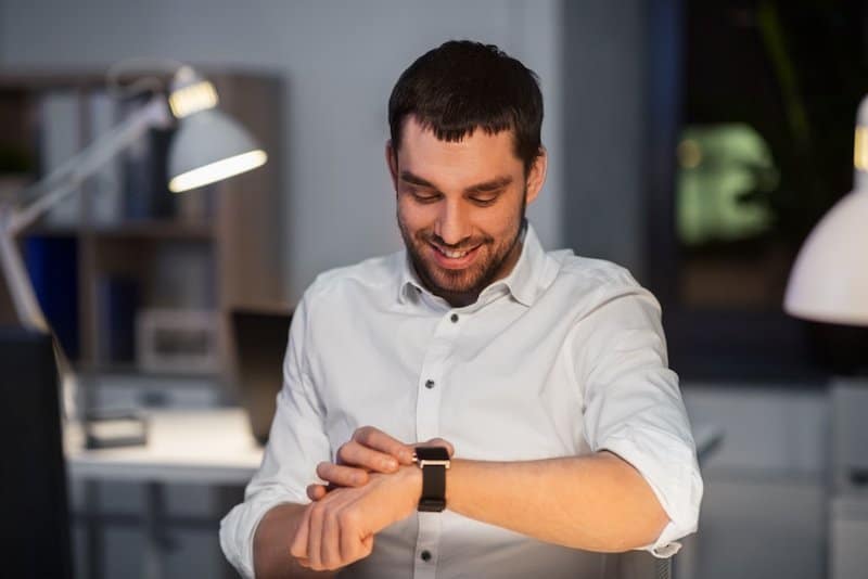 Projektmitarbeiter schaut auf seine Uhr und lächelt