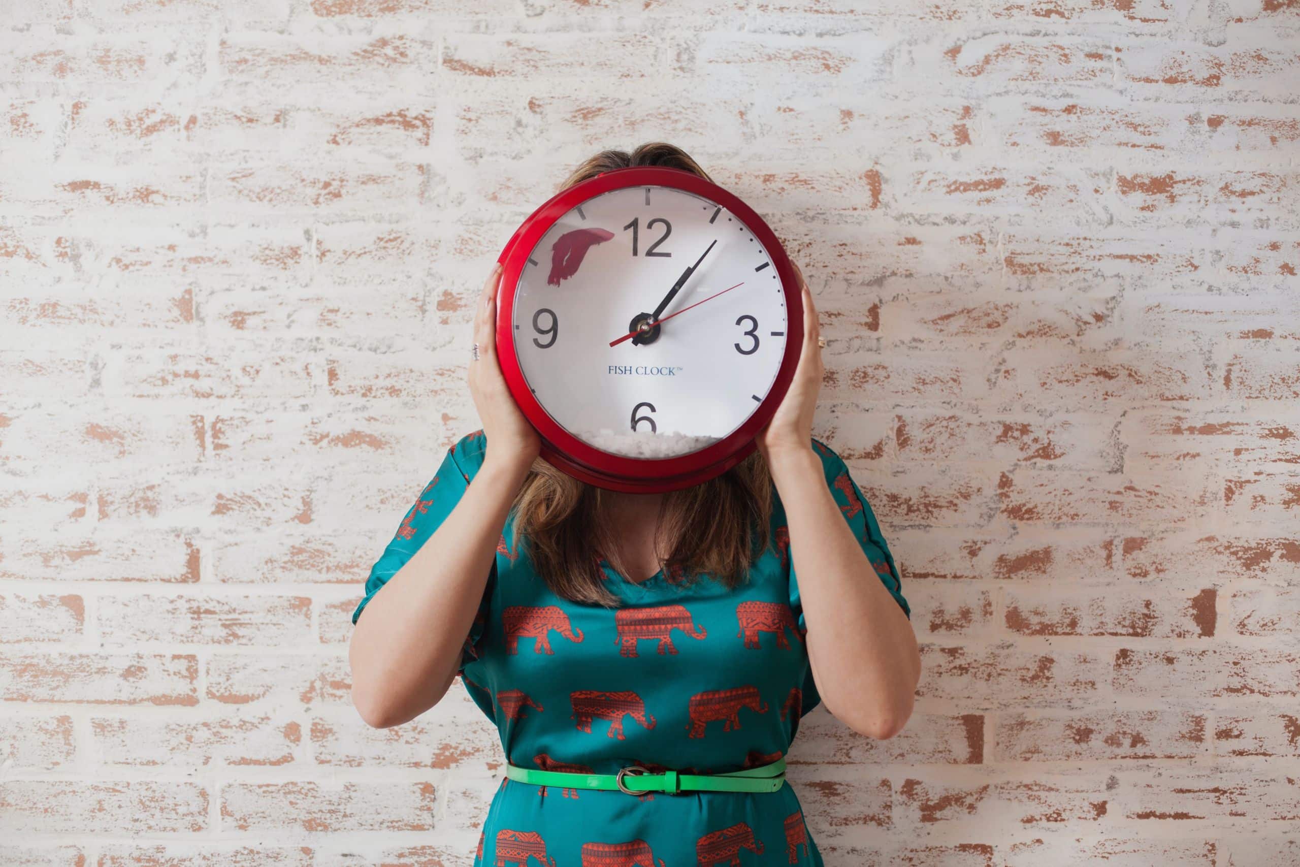 Eine Frau hält eine Uhr vor das Gesicht