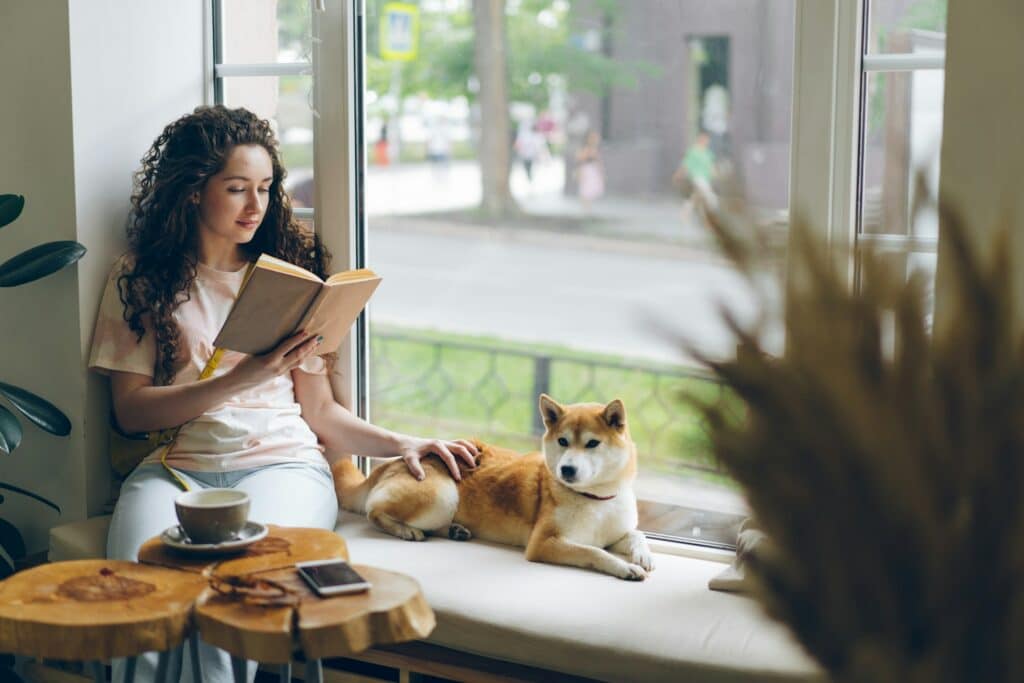 Work-Life-Blending: Flexibles Arbeiten neu gedacht Eine Frau sitzt neben ihrem Hund am Fenster und liest