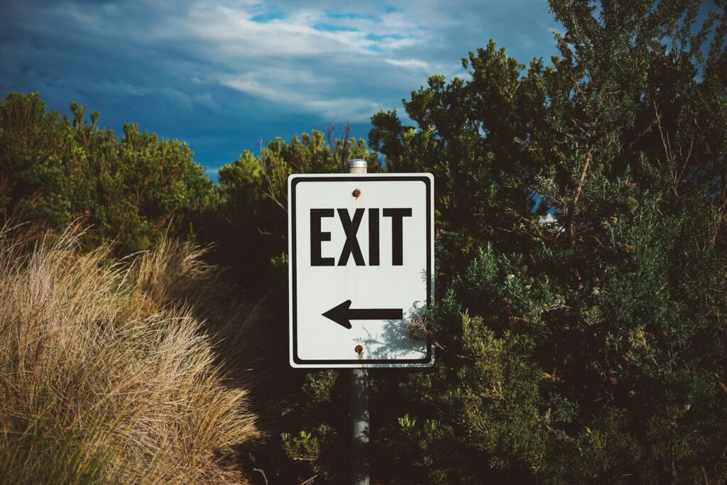 Die Offboarding-Checkliste: Alle Schritte im Überblick Inmitten von grünen Büschen steht ein Schild mit der Aufschrift "Exit"