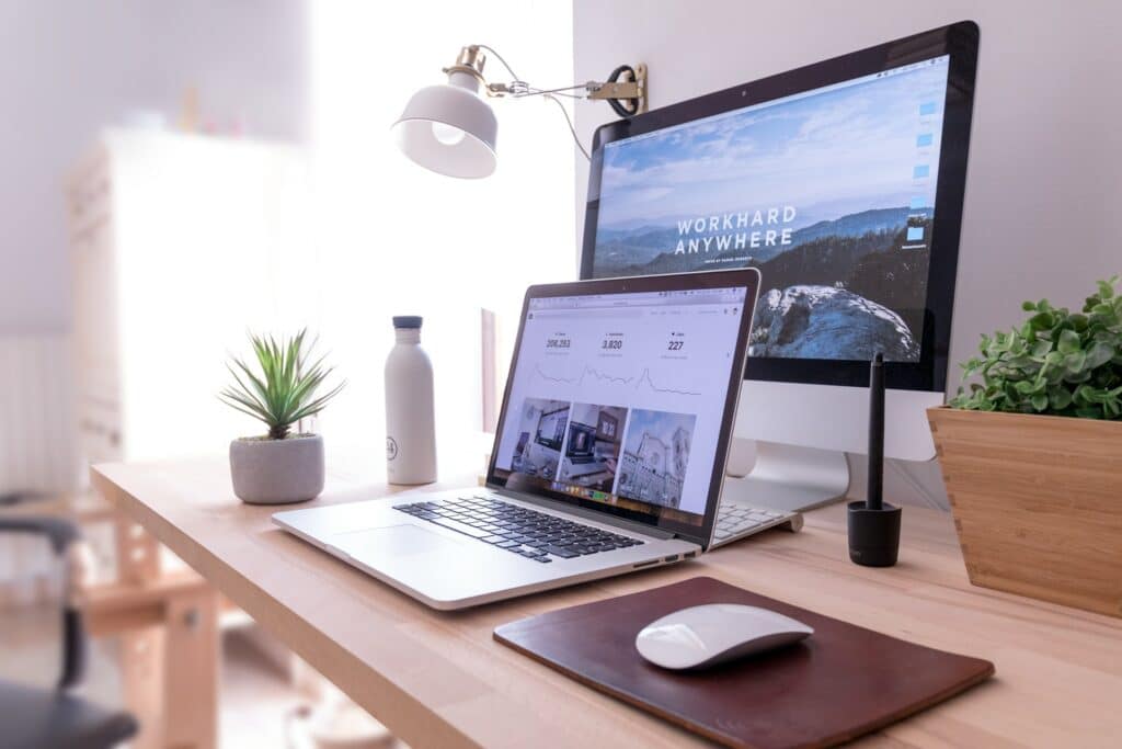 Desk Sharing Konzept: Definition, Vorteile & Regeln Ein Schreibtisch auf dem ein Laptop und dahinter ein Bildschirm steht.