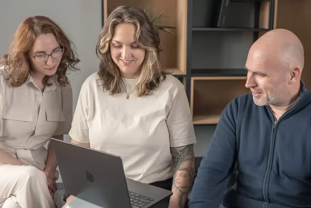 3 Teammitglieder betrachten etwas auf ihrem Notebook