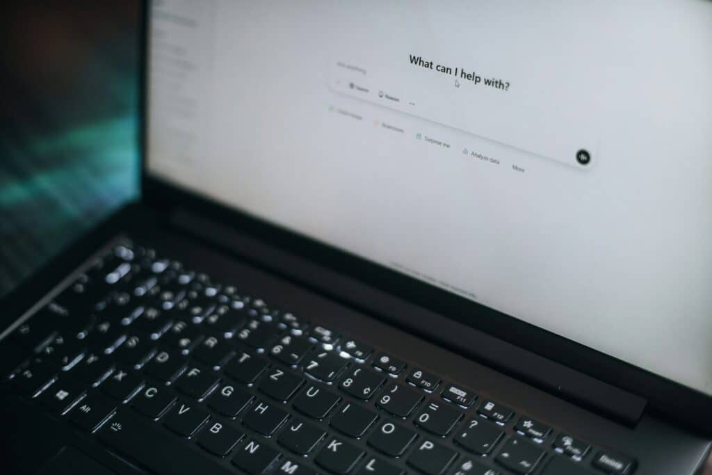 Ein Foto von einem Laptop auf dessen Bildschirm das Dialogfenster eines KI Chat-Tools zu sehen ist
